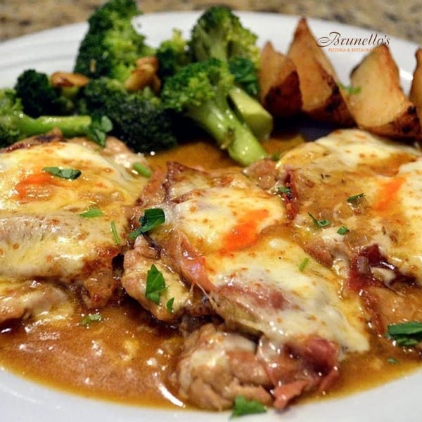 Brunello's Italian dish with melted cheese, brown sauce, broccoli, and potato wedges on a white plate.